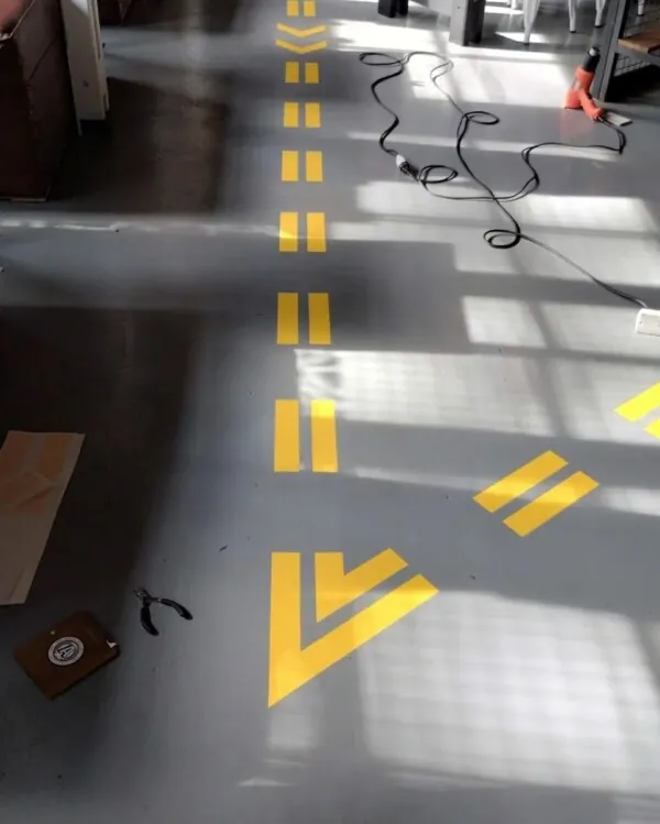 Señalética de piso con vinilo amarillo en un espacio de alto tránsito.